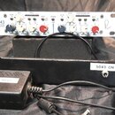 Bílý rackový kompresor s nápisem 5043 Portico Series Duo Compressor. Přední panel obsahuje různé ovladače, přepínače a v centru analogový VU metr s n…