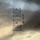 Detailní záběr na povrch kovového činele. Na povrchu je černý nápis LIGHT RIDE a vedle něj menší text 24"/61 cm. Povrch vykazuje drobné škrábance a s…