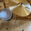 Fotografie zobrazuje část bicí soupravy s čínem na chromovaném stojanu a malým bubnem. Na čínu je vidět logo paiste a nápis pxl 17" 65 Light Weight.…