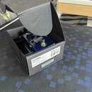 Modrý efekt pedál v černé kartonové krabici. Na horní straně pedálu je bílé logo MXR a nápis BASS OCTAVE, v dolní části je vidět nápis OUTPUT a GROWL…