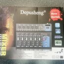 Fotografie znázorňuje krabici s míchací deskou. Na krabici je nápis Depusheng®, New Series, Professional MIXER a seznam technických parametrů. Uprost…
