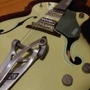 Světle žlutá polodupatá elektrická kytara s f-otvory a tmavě zeleným pickguardem, na kterém je nápis GRETSCH. Nástroj má chromovaný most a vibrační s…