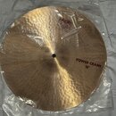 Zlatavý kovový činel v originálním plastovém obalu. Na povrchu je nápis POWER CRASH 16" a logo Paiste s označením 900. V horní části je štítek s text…