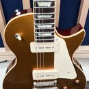 Hnědá elektrická kytara s bílým pickguardem a dvěma humbuckery s krémovými kryty. Nástroj má chromovaný most a čtyři ovládací knoflíky v hnědé barvě.…