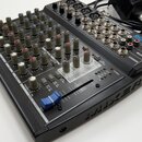 Černý kompaktní mixážní pult s kovovým šasi. Na horním panelu je nápis HS1200CS COMPACT MIXER a logo RHSOUND. Zařízení obsahuje řadu regulačních knof…