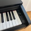 Detailní pohled na klávesnici digitálního piana v černém provedení. Na pravé ovládací liště je vidět vypínač, otočný knoflík s nápisem MASTER VOLUME…