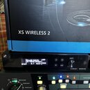 Fotografie zobrazuje bezdrátový přijímač značky SENNHEISER s nápisem XS WIRELESS 2 a digitálním displejem, na kterém je vidět hodnota 548.250 MHz a d…