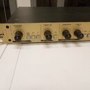 Zlatý rackový procesor s černým šasi. Na levé straně je logo Track One. Přední panel obsahuje čtyři otočné knoflíky s popisky MICROPHONE GAIN (dB), S…
