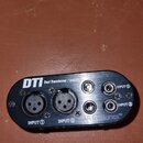 Černý oválný konektor s kovovým povrchem. Na zařízení jsou nápisy DTI, Dual Transformer / Isolator a RTAccessories™. Jsou zde vidět čtyři vstupy, dva…
