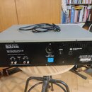Zadní strana šedého elektronického zařízení s kovovým povrchem. Na zadním panelu jsou nápisy „SHOCK HAZARD - DO NOT OPEN !“, „STAAR ELECTRONIC STOP S…