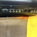 Detail zadní strany černého hudebního přístroje s řadou konektorů a ovládacích prvků. Jsou zde viditelné nápisy MIDI, IN, FOOT SWITCH SUSTAIN ASSIGNA…