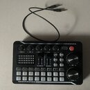 Černý mixážní stolek s ovládacími knoflíky, posuvníky a řadou tlačítek. Na panelu jsou nápisy -TREBLE+, -MID+, -BASS+, -RECORD+ a -Specialeffect+. V…