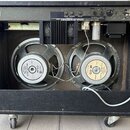 Zadní strana černého kytarového komba s otevřeným zadním panelem, ve kterém jsou vidět dva reproduktory. Na reproduktorech jsou nápisy „Celestion G12…