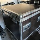 Černý transportní case s hliníkovými hranami a kovovými rohy. Má dvě zapínací zámky na horní straně a dvě madla z boků. Povrch vykazuje známky opotře…