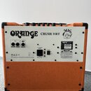 Zadní strana kytarového komba v oranžovém vinylu s bílým zadním panelem. Na panelu je nápis ORANGE CRUSH 35RT a logo značky Orange. Jsou zde vidět vs…