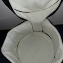 Otevřený černý pouzdro s bílou, měkkou vnitřní výplní z materiálu připomínajícího fleece. Vnitřek je prázdný a má zaoblený tvar. Na povrchu nejsou vi…