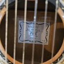 Detail vnitřku akustické kytary s viditelnou štítkem na desce. Na štítku je uveden nápis MIGUEL ALMERÍA, PURE SERIES a STUDENT s označením 1/2. V pra…