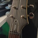 Detail hlavy černé elektrické kytary se stříbrnými ladičkami. Na čele hlavy je bílý nápis schecter a pod ním Diamond Series, na hraně hlavy je svislý…
