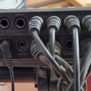 Záběr na zadní panel černého elektronického zařízení. Jsou zde vidět konektory s nápisy VOLUME, R-OUTPUT-L a POWER ON OFF. V levé části je viditelný…
