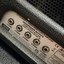 Detail zadní strany zesilovače s bílým kovovým panelem. Na panelu je nápis LITTLE GIANT 5 - SINGLE ENDED/CLASS A AMPLIFIER a LOUDSPEAKER OUTPUTS s do…
