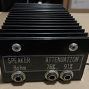 Černý kovový přístroj s výrazným chladicím žebrováním. Na přední straně je štítek s nápisy SPEAKER 8ohm a ATTENUATION 75% 91%. Přístroj obsahuje tři…