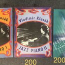 Tři sešity s notami položené vedle sebe. První dva mají oranžové a fialové obaly s nápisy „Vladimír Klusák“, „JAZZ PIANO I“ respektive „JAZZ PIANO II…
