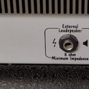 Detail zadní strany bílého přístroje s třemi konektory. Nad konektory jsou nápisy External Loudspeaker, Head Phones a Reverb Remote. U prvního konekt…