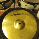 Zlatý cymbál typu splash položený na černém texturovaném podkladu. V horní části je černé logo „Anatolian“. Dole je nápis „Ultimate 12"/30cm Splash“.…
