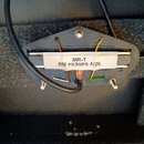 Fotografie znázorňuje elektrický snímač s černým plastovým základem a bílou nálepkou. Na nálepce je uveden nápis MR-T RM PICKUPS 4/26. Ze snímače ved…