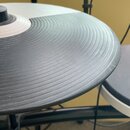 Fotografie zachycuje detail elektronického činely v černo-bílé variantě. Povrch je opatřen koncentrickými drážkami a vykazuje známky opotřebení ve fo…