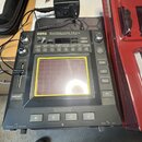 Černý kontrolér KORG Kaossilator Pro+. Zařízení má uprostřed čtvercový dotykový panel s žlutým rámečkem a nad ním řadu tlačítek s čísly 1 až 8. Na ho…