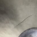 Detailní záběr na povrch kovového činele s koncentrickými drážkami. V pravé části je viditelná trhlina v materiálu. Na fotografii nejsou žádné značky…