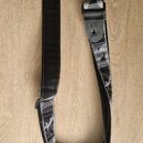 Černý popruh na hudební nástroj s šedými dekorativními pruhy. Na popruhu je několikrát viditelné bílé logo Fender. Povrch vykazuje mírné známky použí…