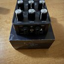 Černý kytarový pedál s šesti ovládacími knoflíky a dvěma spínači v horní části. Na přední straně jsou nápisy OUTPUT, REVERB a VOLUME. Zadní panel obs…