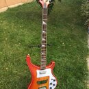 Elektrická basová kytara s trupem v oranžovo-žlutém přechodovém odstínu (sunburst) a bílým pickguardem. Na hlavě hmatníku je viditelné logo výrobce,…