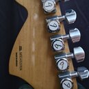 Zadní strana hlavy kytary z přírodního dřeva s šesti chromovanými ladičkami. Na dřevě je vidět kulaté logo s nápisy „Fender“ a „SPECIAL EDITION“. V d…