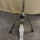 Chromovaný stojan s pedálem, pravděpodobně hi-hat. Na stupni pedálu je viditelný nápis MAPEX. Povrch chromu je lesklý, na spodní části nohou jsou čer…