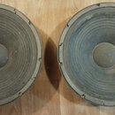 Dvě velké kruhové reproduktory s šedými membránami a vnějším kovovým rámem. Povrch membrán je znečištěný prachem a vykazuje známky opotřebení. Na fot…