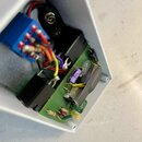 Fotografie zachycuje vnitřek bílého kovového šasi s elektronickým zapojením na zelené desce plošných spojů. Jsou zde vidět dva černé transformátory,…