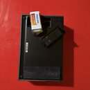 Fotografie zachycuje zadní stranu černého elektronického zařízení. V horní části je umístěna baterie s nápisy PHILIPS, Extra Zinc Chloride a W 1212.…