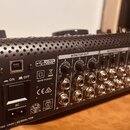 Záběr na zadní panel černého mixážního pultu s kovovým povrchem. Jsou zde viditelné nápisy USB INTERFACE, MADE IN CHINA, MONITOR OUT, RECORDING OUT,…