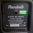 Fotografie zachycuje štítek na zadní straně hudebního přístroje. Na černém pozadí je bílý nápis Randall®, zelený štítek RoHS conform a text MODEL NO.…