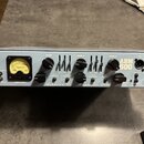 Šedý basový zesilovač s ovládacím panelem. Na přední straně je nápis Ashdown Bass Magnifier EVO IV a označení modelu ABM 600. Zařízení obsahuje analo…