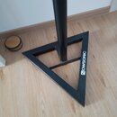 Černý kovový stojan s trojúhelníkovou základnou. Na jedné straně základny je bílý nápis NOWSONIC. Povrch vykazuje mírné známky opotřebení v podobě dr…