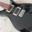 Černá elektrická kytara s lesklým povrchem a hnědým hmatníkem. Nástroj má dva humbuckery s krémovými rámečky, jeden přepínač a dva ovládací knoflíky.…