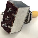 Fotografie znázorňuje elektrický přepínač s kovovým krytem a béžovým plastovým knoflíkem. Na spodní straně je hnědý textalit s několika pájecími kont…