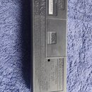 Zadní strana černého ladicího zařízení z plastu. Je zde uveden nápis BOSS Corporation, MODEL: TU-12EX a CHROMATIC TUNER. Na bílém štítku je sériové č…