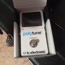 Bílý kytarový ladič v originální krabici. Na přední straně je nápis „polytune®“, pod ním text „true bypass“ a ve spodní části logo „tc electronic“. V…