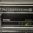 V hliníkovém racku jsou umístěna dvě černá zařízení značky Ampeg. Horní jednotka nese nápis SVPCL ALL TUBE BASS PREAMP a má řadu ovládacích knoflíků…
