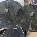Dvě černé perforované činely z kovu s jemnou mřížkou otvorů. Pod nimi je vidět černý buben s bílým nápisem EVANS a pod ním menším písmem HD ONE. Povr…